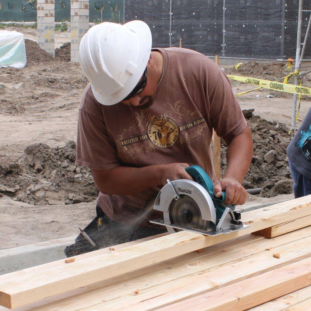 Technician in a hard hat making a precise rip cut with the Makita 15 AMP circular saw, highlighting the visibility provided by the integrated dust blower.