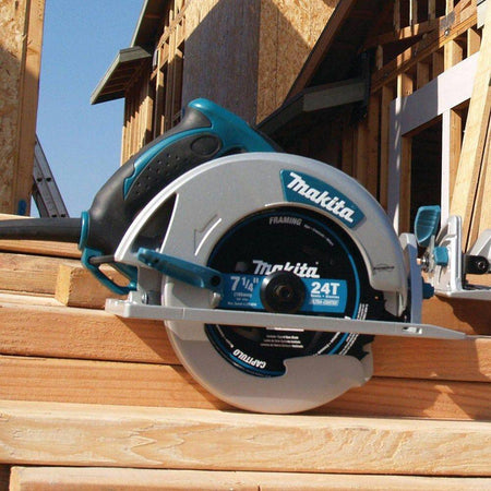 Side view of the Makita circular saw resting on stacked lumber at a residential construction site, highlighting the professional industrial design and magnesium components.