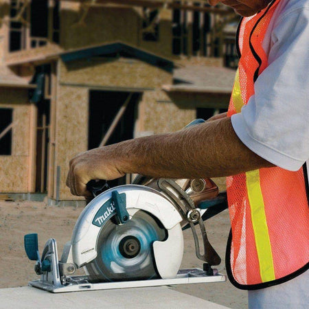 Technician utilizing the Makita 5377MG magnesium circular saw on a construction site, demonstrating the high-performance cutting capabilities and the visibility provided by the wide visibility window.