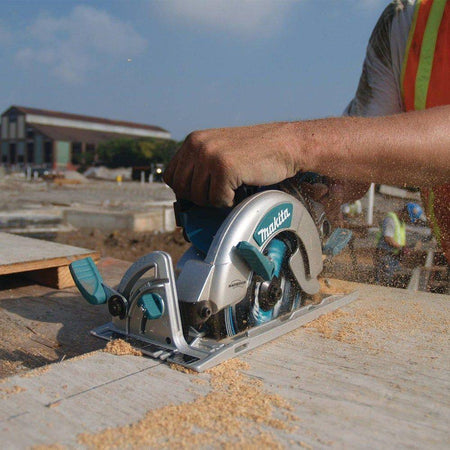 A professional builder in safety gear guiding the Makita 15 AMP hypoid saw through a long rip cut on a wooden board, showcasing the tool's power and efficiency for general contractors.