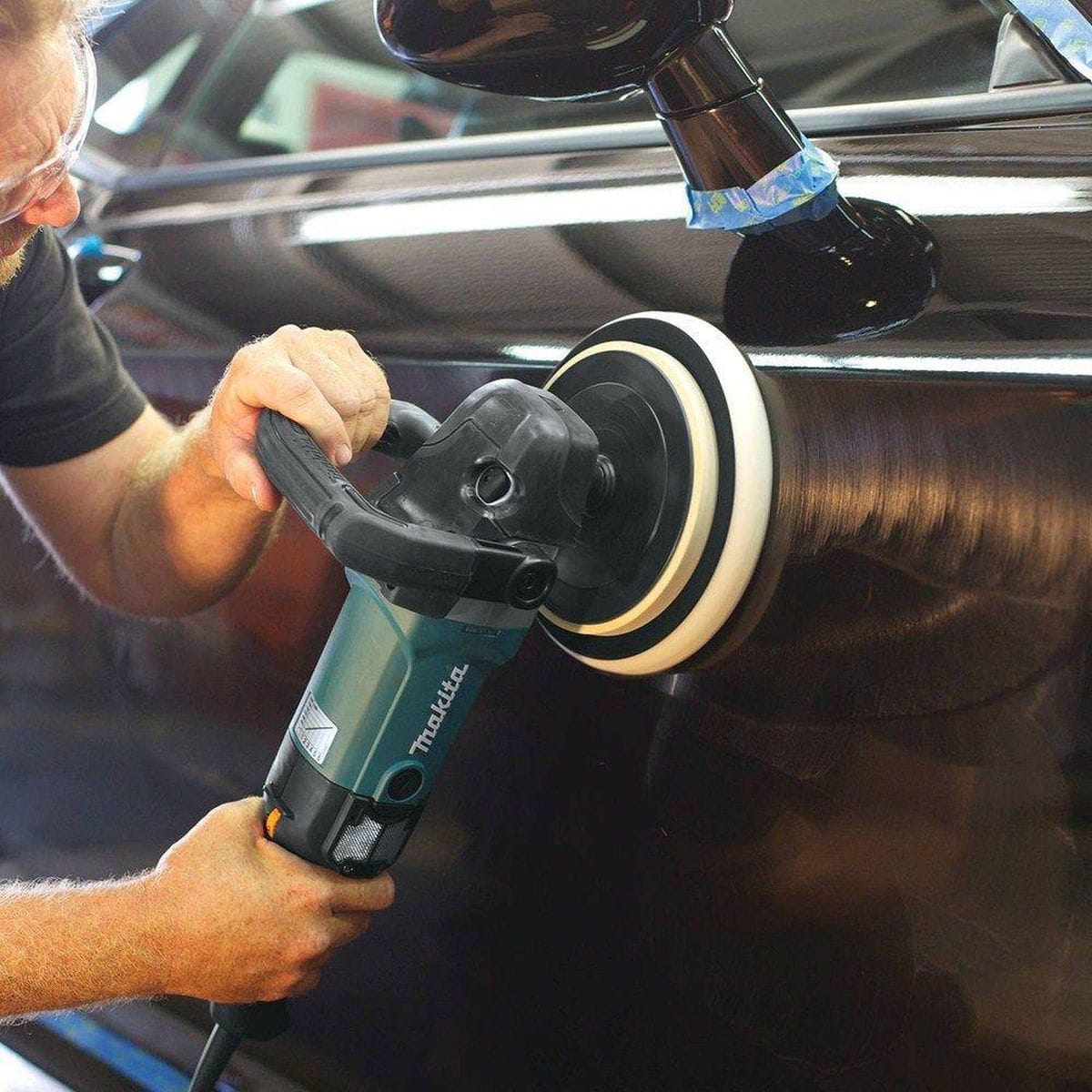 A technician wearing a face shield uses the Makita corded polisher to perform professional-grade surface finishing on a pre-cast concrete slab, illustrating effective dust and slurry control.
