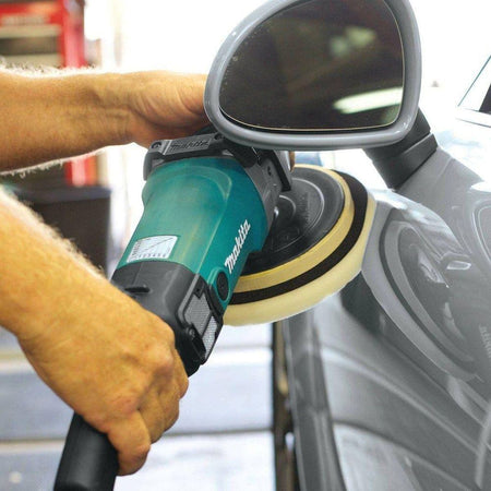 Close-up action shot of the Makita 7-inch variable speed polisher in use on a wet concrete surface, showcasing the high-torque performance needed for stone and decorative finishing.