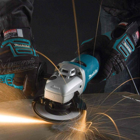 An action-oriented perspective of the Makita 9565PCV angle grinder with a paddle switch being used on a metal surface, emphasizing the ergonomic grip and high-torque capability.