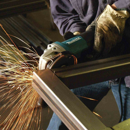 Close-up action shot of the Makita 5-inch corded angle grinder equipped with a cutting wheel to precisely slice through square metal tubing in a fabrication shop.