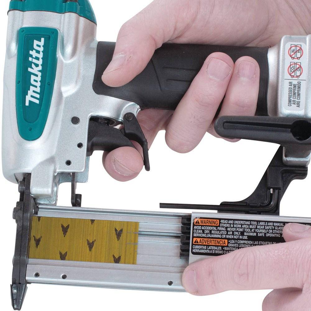 A woodworker loading a strip of 23 gauge headless pins into the self-adjusting side drop-in magazine of the Makita AF353 pneumatic pin nailer.