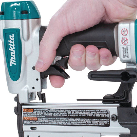 Close-up of a hand comfortably gripping the Makita AF353 pneumatic pin nailer, demonstrating the ergonomic rubber soft grip and the controlled double two-finger trigger.
