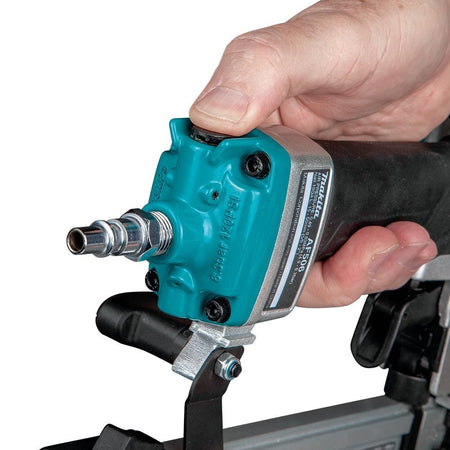 A close-up of a hand pressing the built-in air duster button on the back of the Makita AF506 nailer's handle.