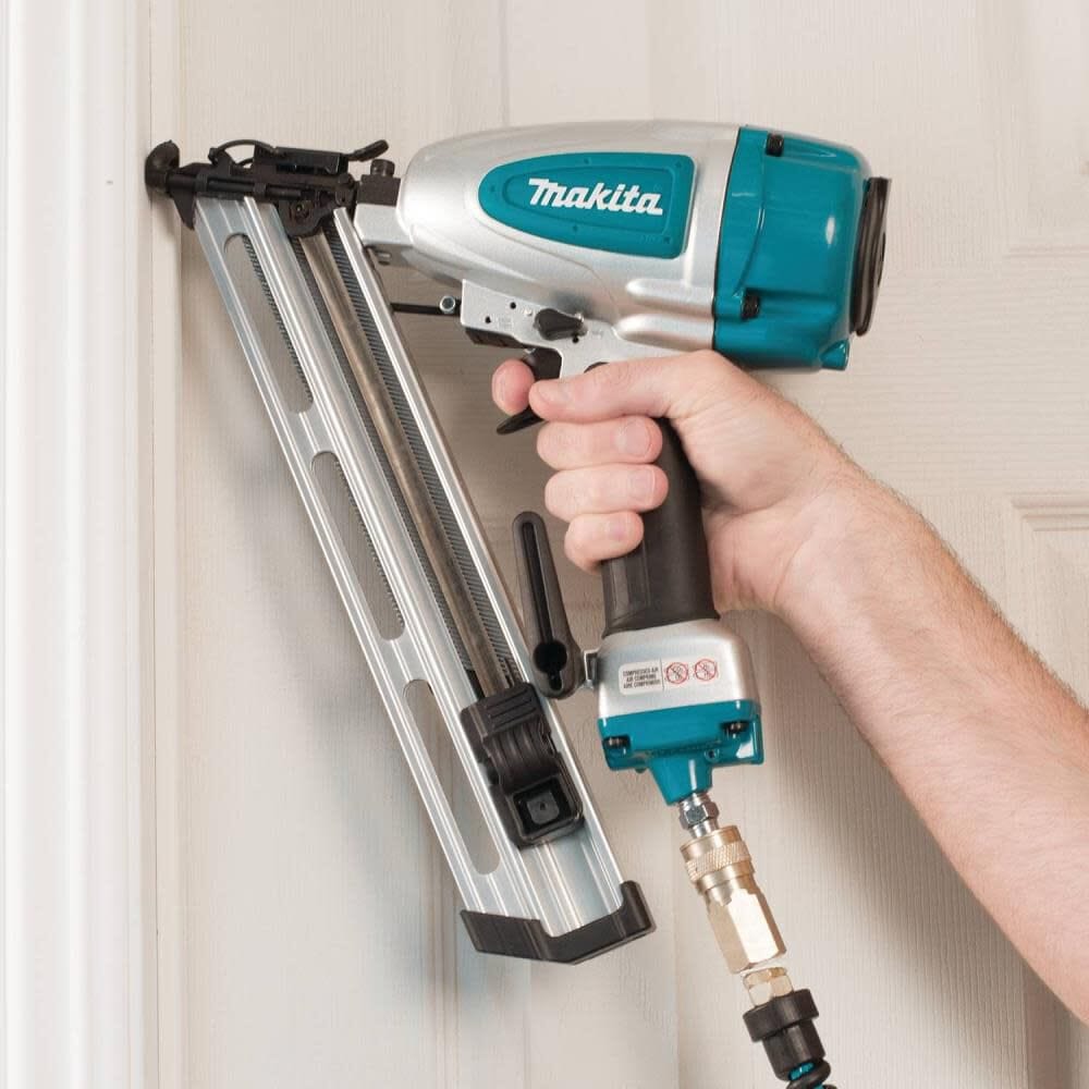 A professional carpenter using the Makita AF635 pneumatic 15 gauge angled finish nailer to securely install white crown molding trim during a woodworking project.