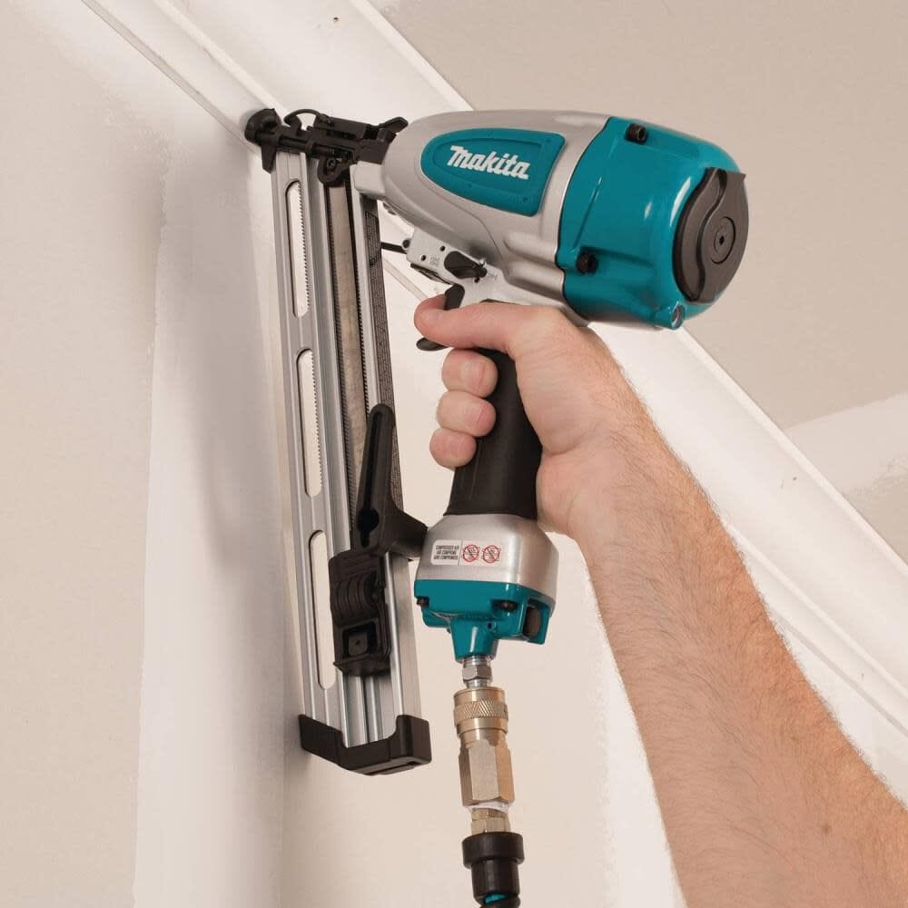 Hand holding a Makita nail gun against a white wall