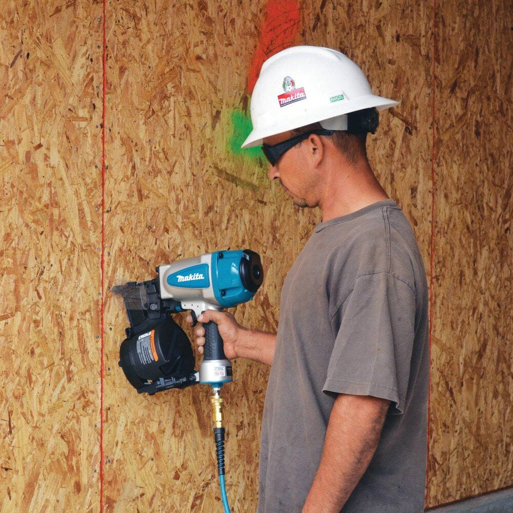 Action shot of a builder using the Makita AN902 pneumatic coil framing nail gun to securely fasten exterior sheathing board to a residential wall frame.