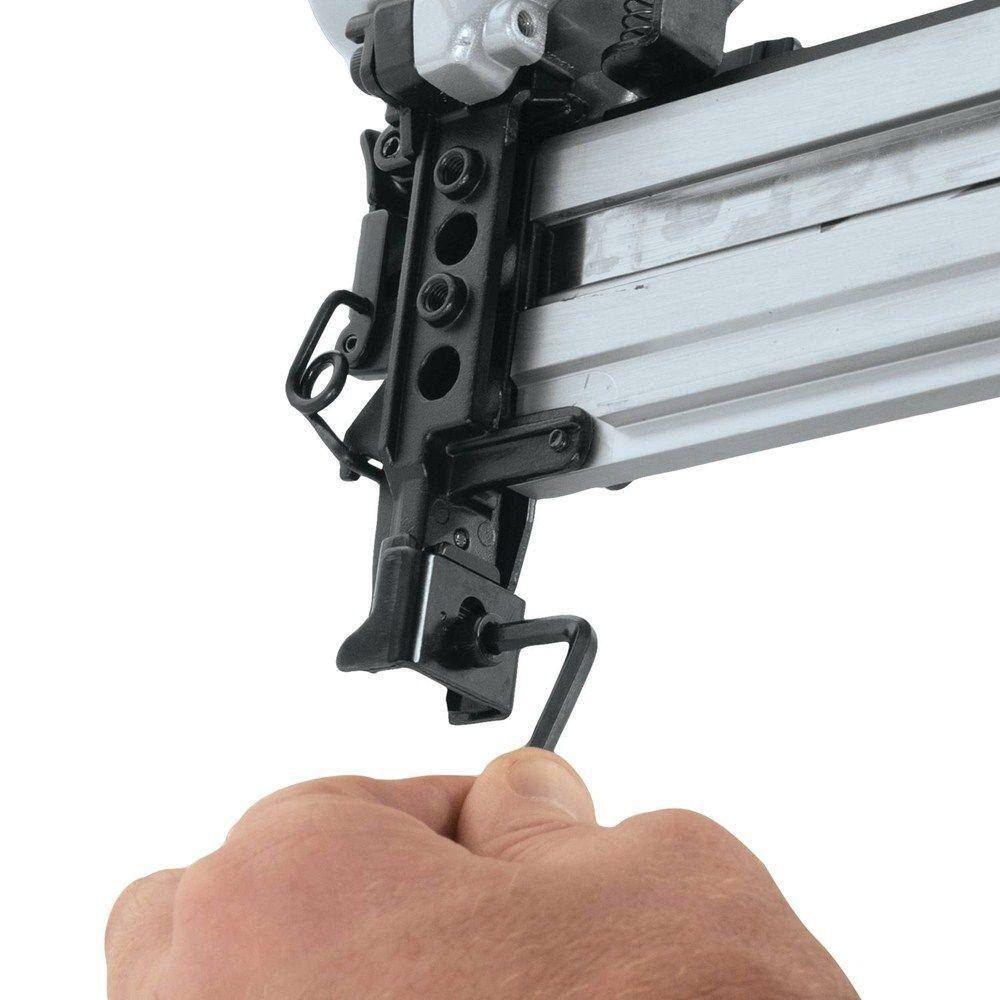 Action shot of a professional woodworker using the Makita AT1150A pneumatic medium crown stapler to securely fasten a large wooden panel during construction.