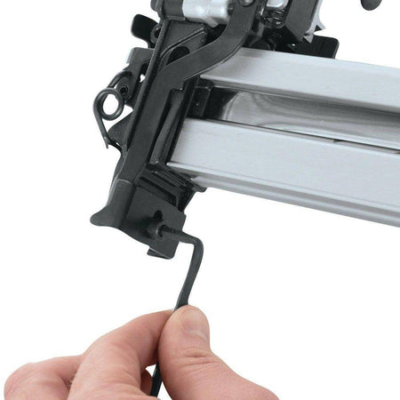 User adjusting a screw on a Makita pneumatic stapler using an Allen wrench, demonstrating routine maintenance and setup for the AT2550A wide crown stapler.