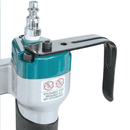 Air inlet and connection point on a Makita pneumatic tool with safety icons and compressed air label, showing the air supply interface used on the AT2550A stapler.