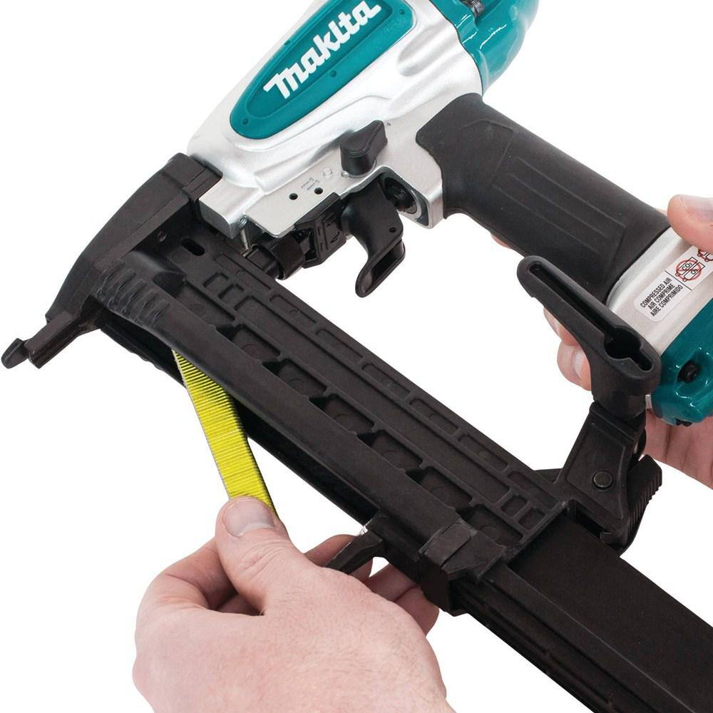 A woodworker loading a strip of 18 gauge 1/4 inch narrow crown staples into the high-efficiency bottom-loading magazine of the Makita AT638A pneumatic stapler.