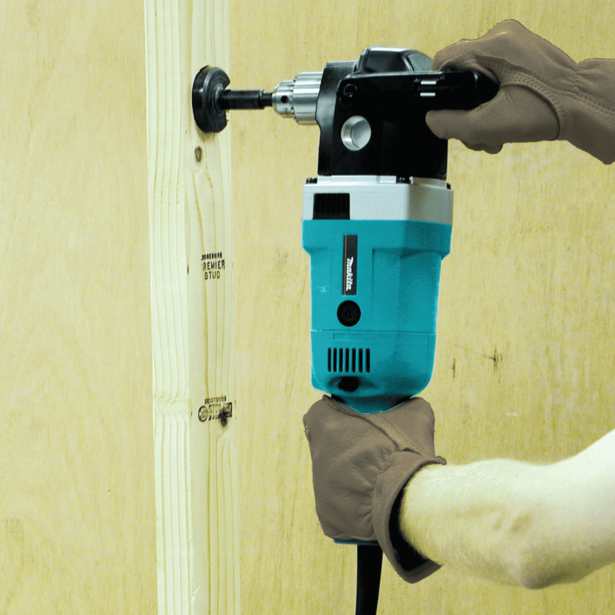 Tradesperson using the Makita angle drill to bore a clean hole through a wooden framing stud during rough-in construction.