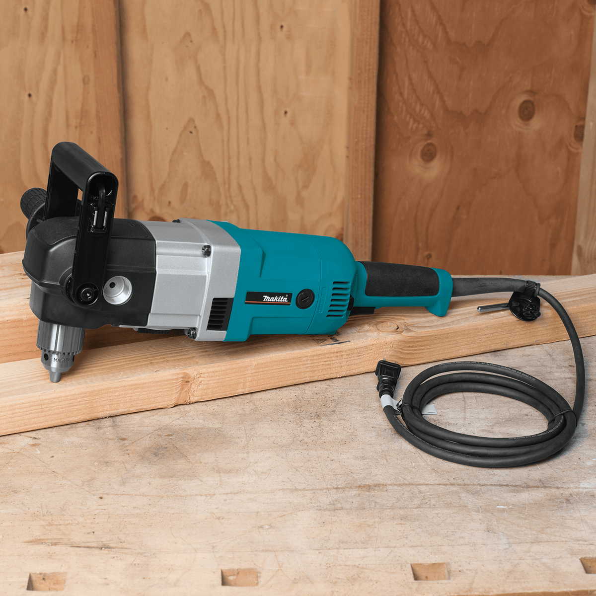 Makita DA4031 right angle drill resting on a jobsite lumber board with its coiled power cord ready for action.