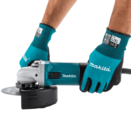 Operator wearing protective gloves gripping the Makita 9566CVR angle grinder during heavy-duty cutting operations.