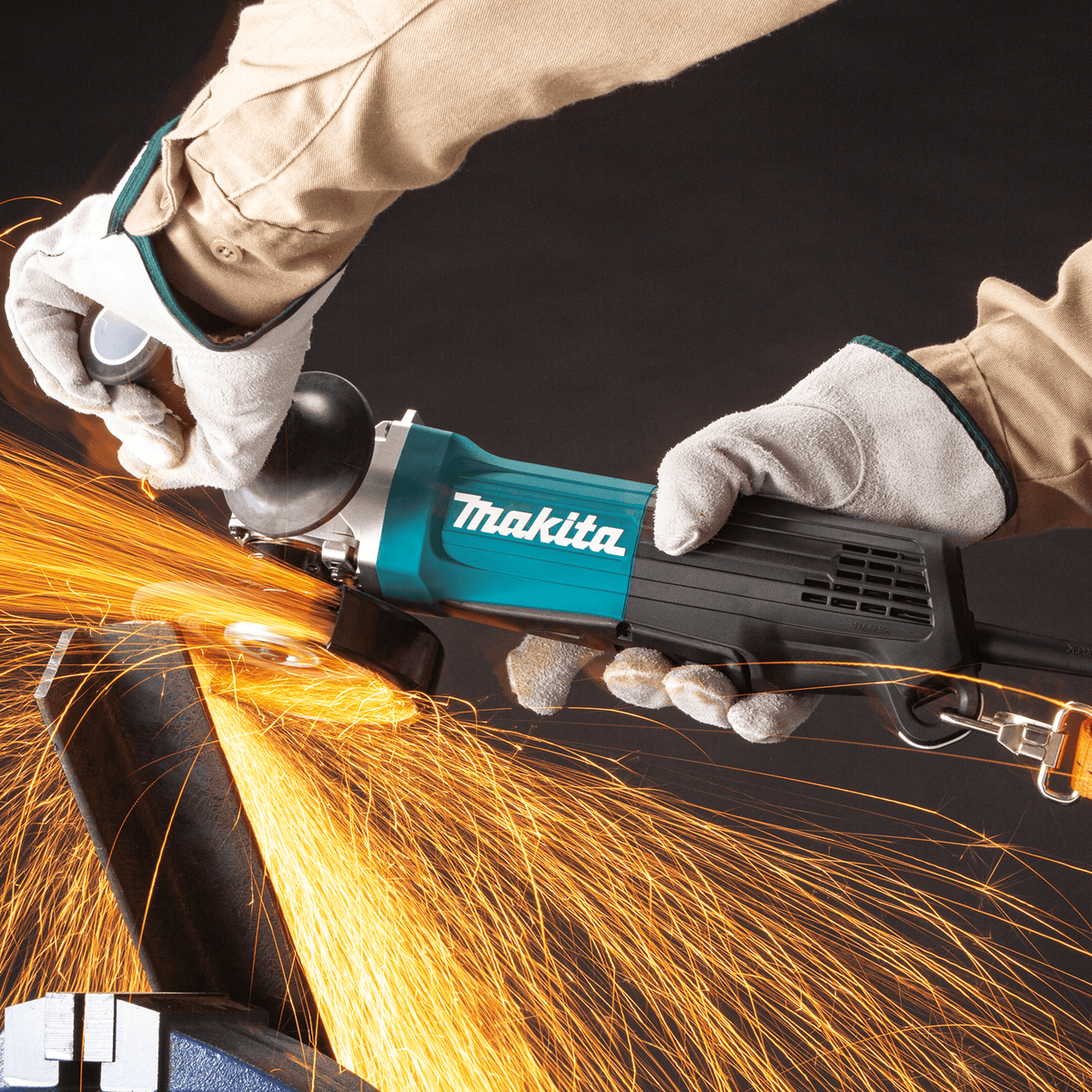 Fabricator grinding a steel angle iron workpiece using the Makita GA4553R angle grinder with safety lanyard connected.