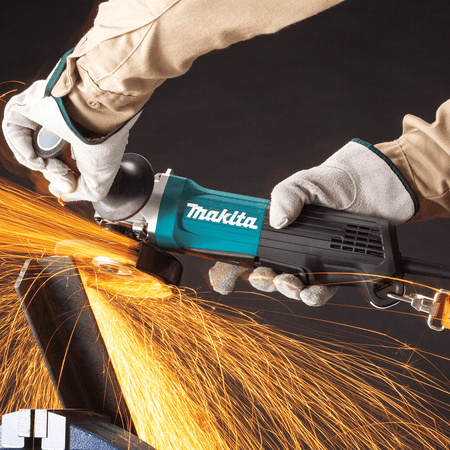 Fabricator grinding a steel angle iron workpiece using the Makita GA4553R angle grinder with safety lanyard connected.