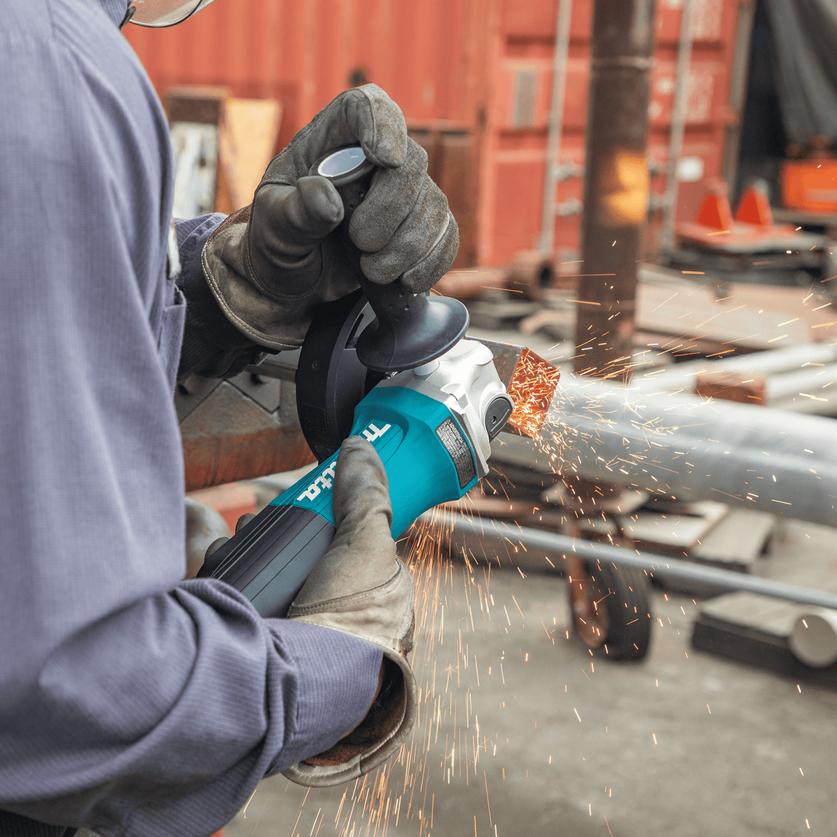 Contractor beveling a steel square tubing stock in an outdoor yard with the Makita GA5052 corded angle grinder.