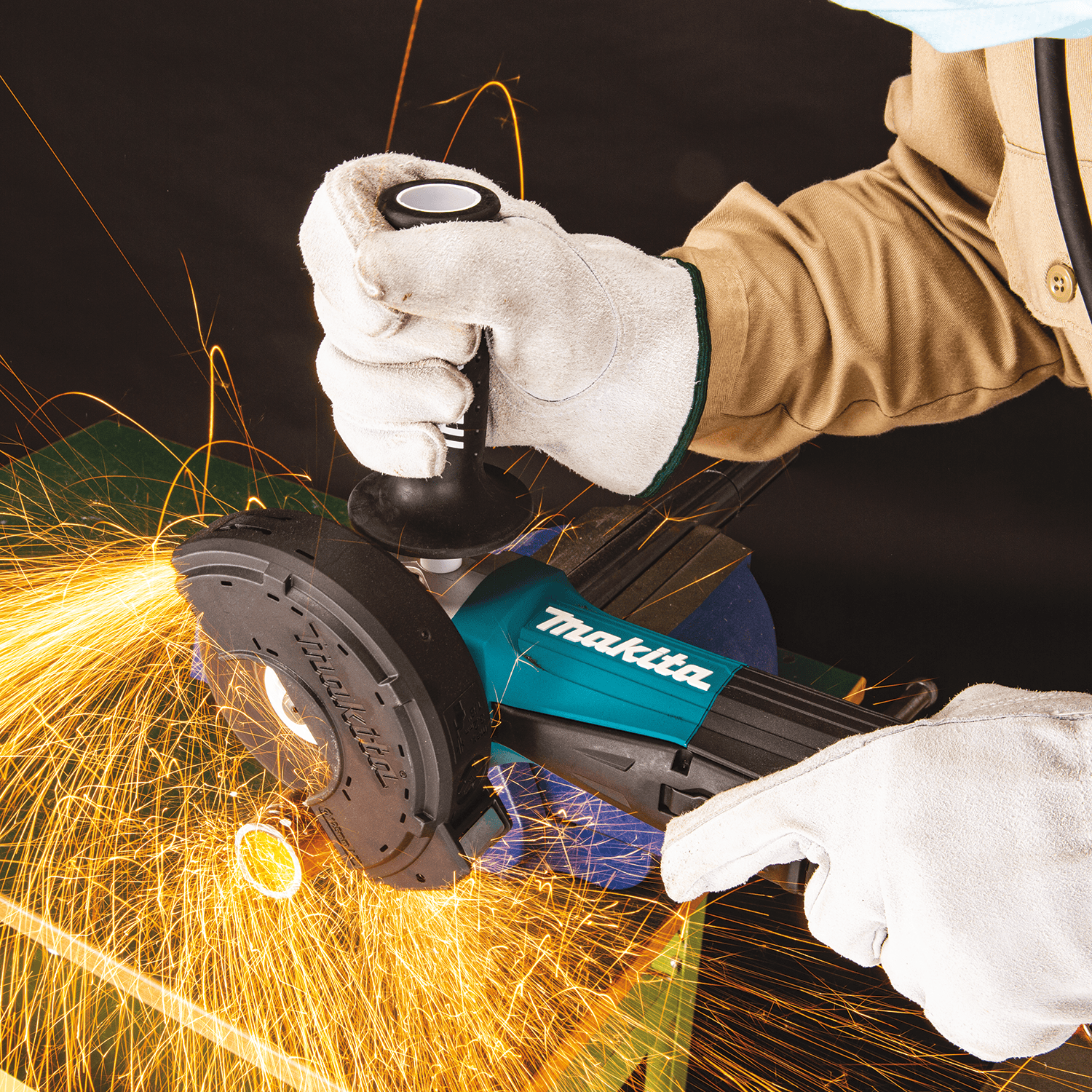 Metal fabricator cutting steel conduit with the Makita GA5052 angle grinder fitted with a dust-collecting cutting guard while throwing sparks.