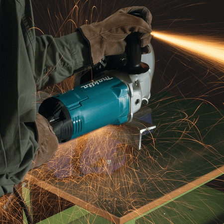 Metal worker using the Makita GA9060 angle grinder to grind down structural steel angle iron welds while throwing sparks.