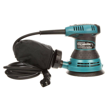 Full product kit view showing the Makita BO5030K random orbit sander, a high-capacity fabric dust bag with nozzle, and the heavy-duty teal hard carrying case for jobsite portability.