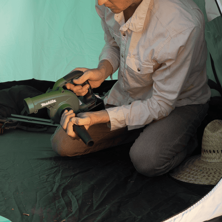 Camper holding the compact Makita ADBU05Z 18V blower inside a camping tent to prepare the floor prior to sweeping out dry dirt.
