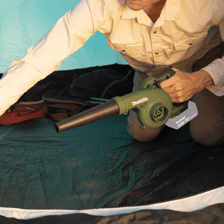 Camper using the 219 MPH airflow from the Makita ADBU05Z 18V LXT blower to quickly sweep sand and leaves off a tent floor.