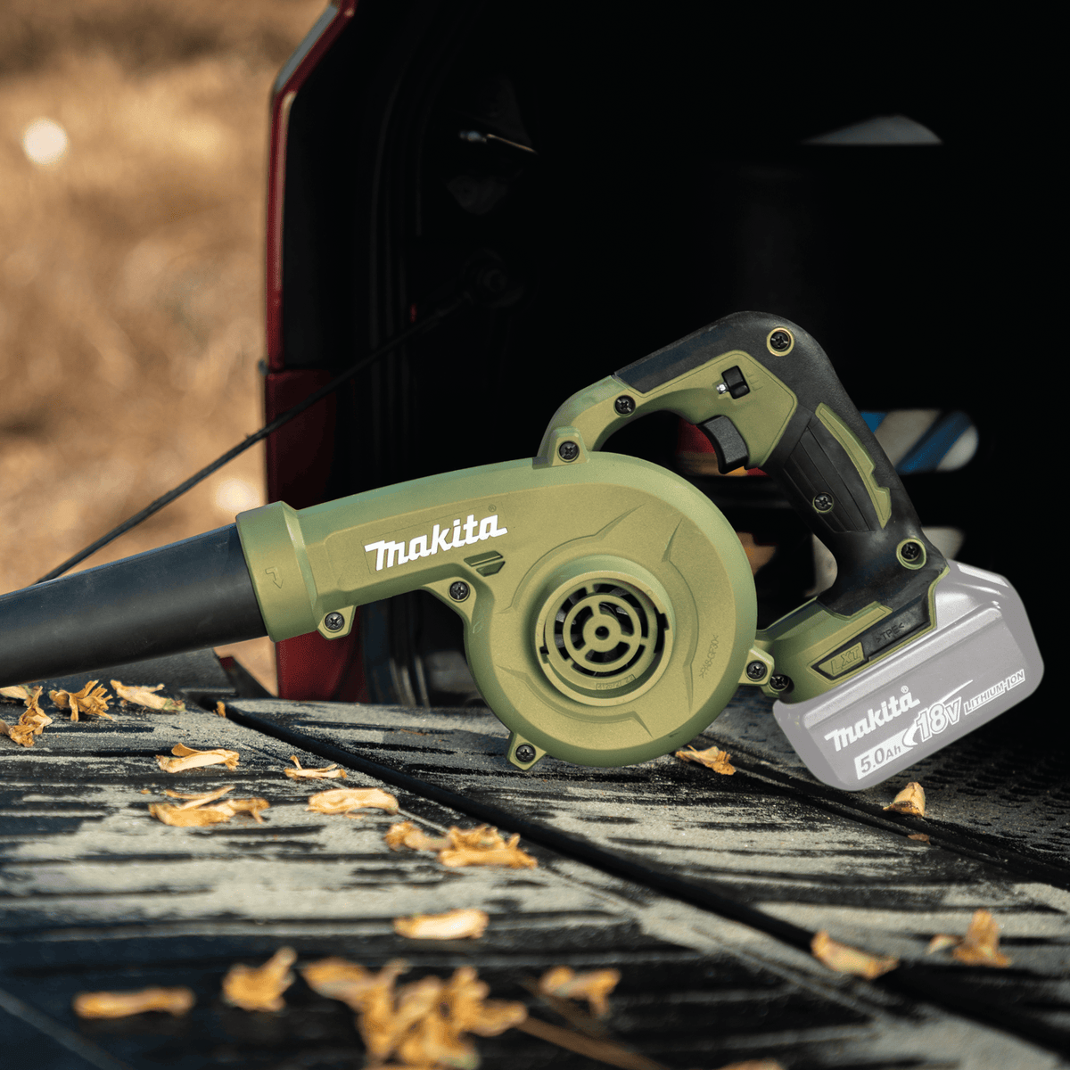 Makita ADBU05Z 18V cordless blower blowing dry leaves and debris off a pickup truck bed liner using 113 CFM air volume.