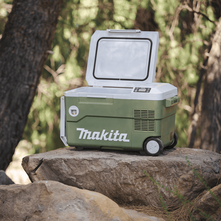 Open Makita ADCW180Z 21-quart cooler resting on a boulder in an outdoor campsite setting showing its insulated storage lid seal.