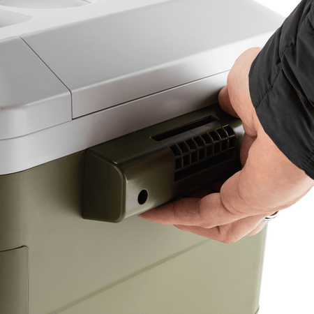 Gloved hand lifting the Makita ADCW180Z cooler using its heavy-duty side carrying handle for two-person transport.