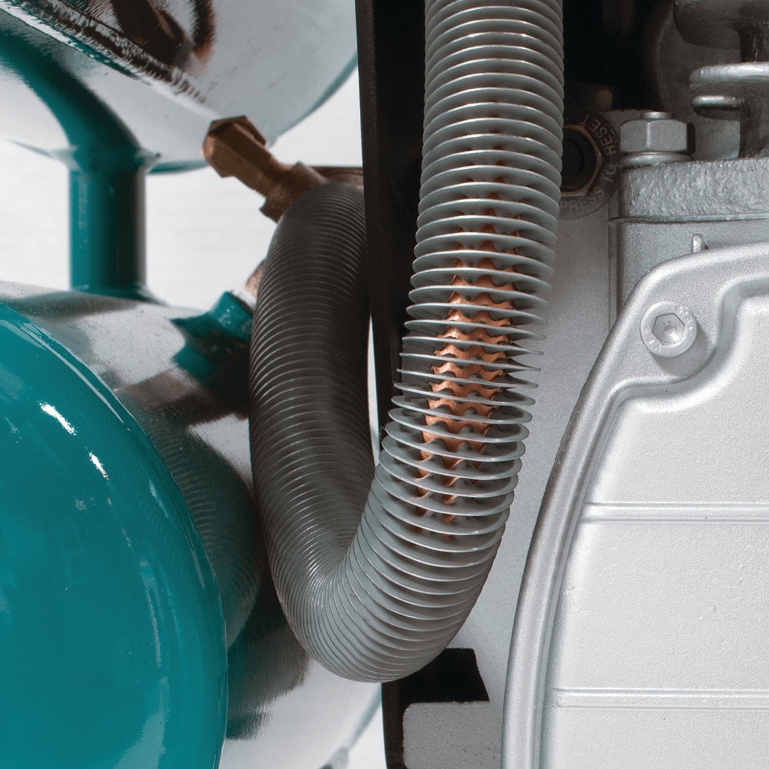 Copper-finned discharge tubing on the Makita MAC2400 compressor dissipating heat to minimize moisture buildup.