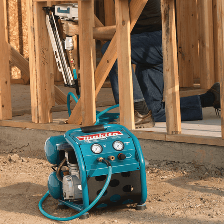 Carpenter using the Makita MAC2400 twin-stack air compressor to drive framing nails on a residential jobsite.