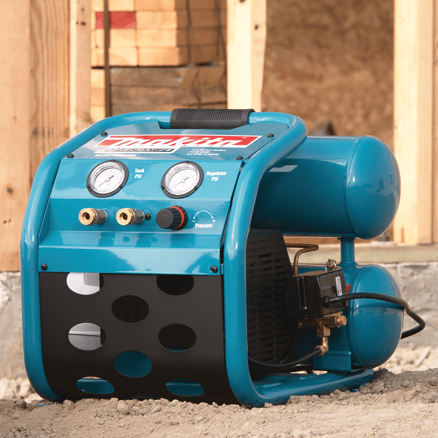 Makita MAC2400 4.2-gallon twin-stack electric air compressor resting on dirt ground at a residential jobsite.