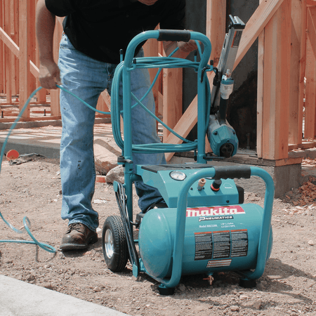 Makita MAC5200 3.0 HP compressor setup on dirt terrain with coiled hose wrap and pneumatic framing nailer hanger.