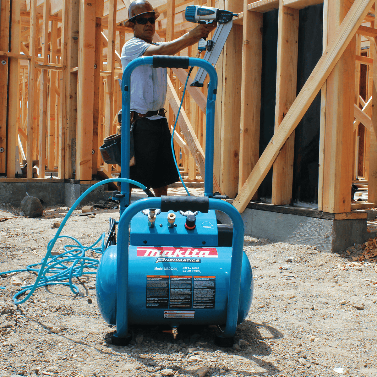 Framer operating a pneumatic nailer powered by the Makita MAC5200 dual-coupler 3.0 HP electric air compressor.