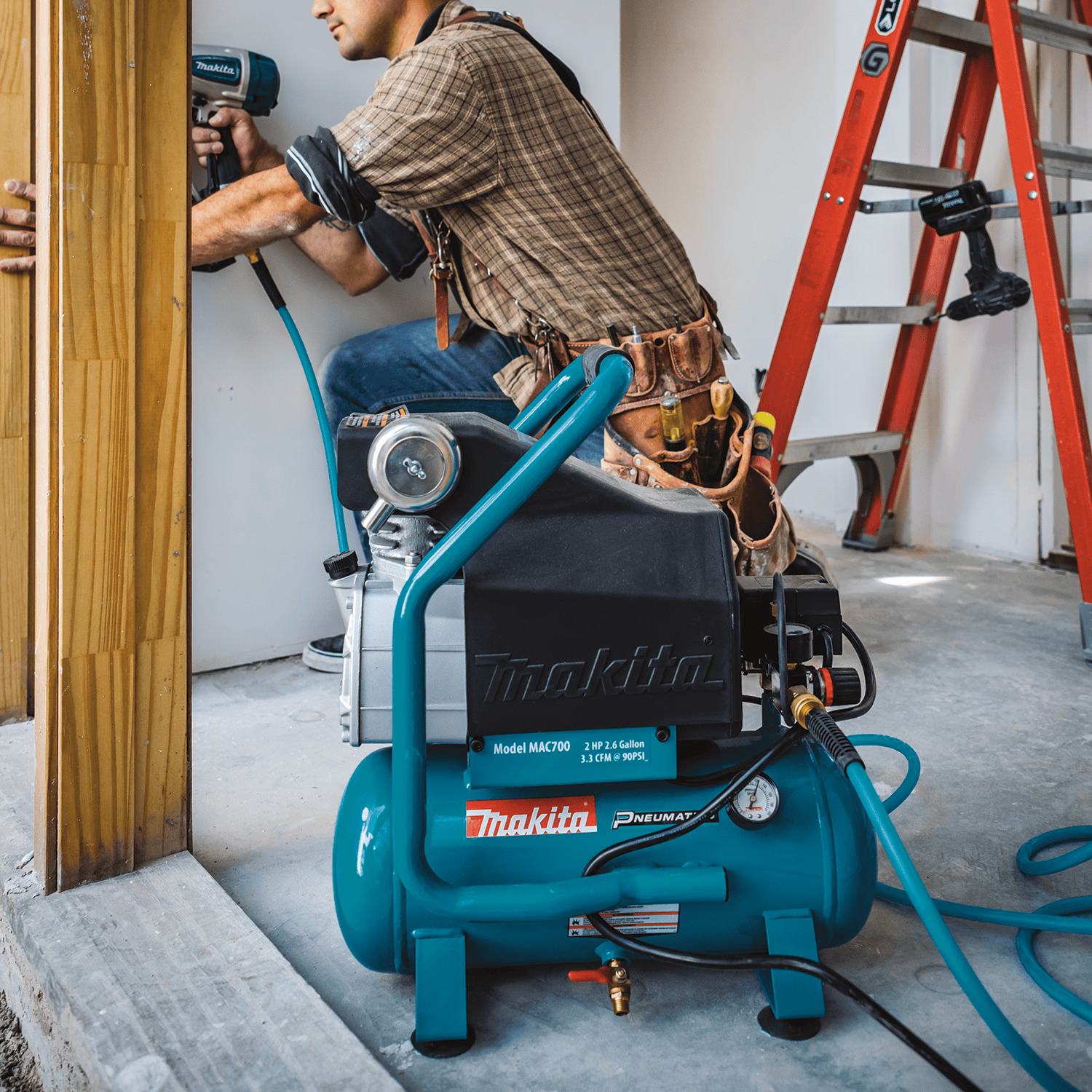 Carpenter operating a pneumatic finish nailer powered by the quiet 80 dB Makita MAC700 air compressor on an interior jobsite.