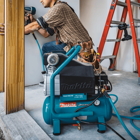 Carpenter operating a pneumatic finish nailer powered by the quiet 80 dB Makita MAC700 air compressor on an interior jobsite.