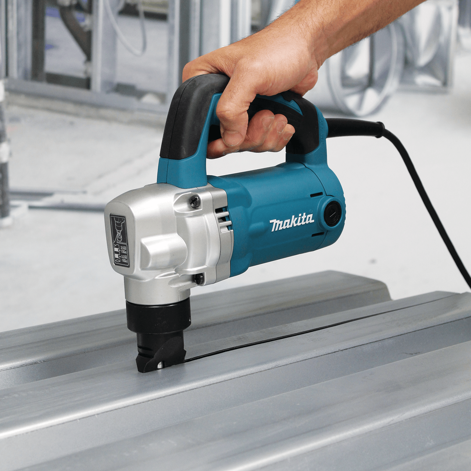 Roofing contractor guiding the Makita JN3201 nibbler across corrugated metal decking while discharging waste chips downward away from the finish.