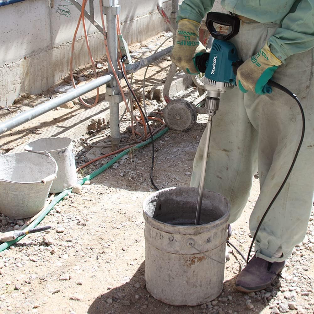Tile installer holding the Makita DS4012 drill with a long paddle bit to mix heavy thinset mortar on a concrete job site.