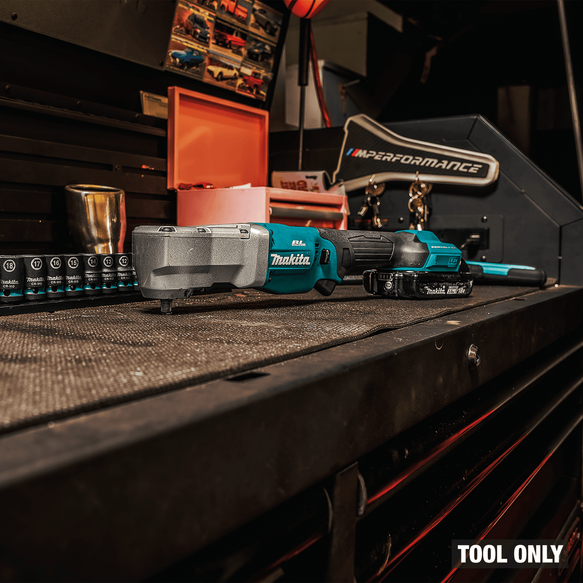Makita XLT03Z 18V cordless 3/8-inch angle impact wrench resting on a shop tool chest beside a metric impact socket set.