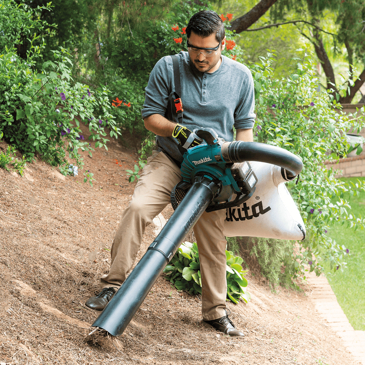 Operator actively vacuuming and shredding organic garden debris using the Makita XBU04PTV kit.