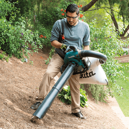 Operator actively vacuuming and shredding organic garden debris using the Makita XBU04PTV kit.