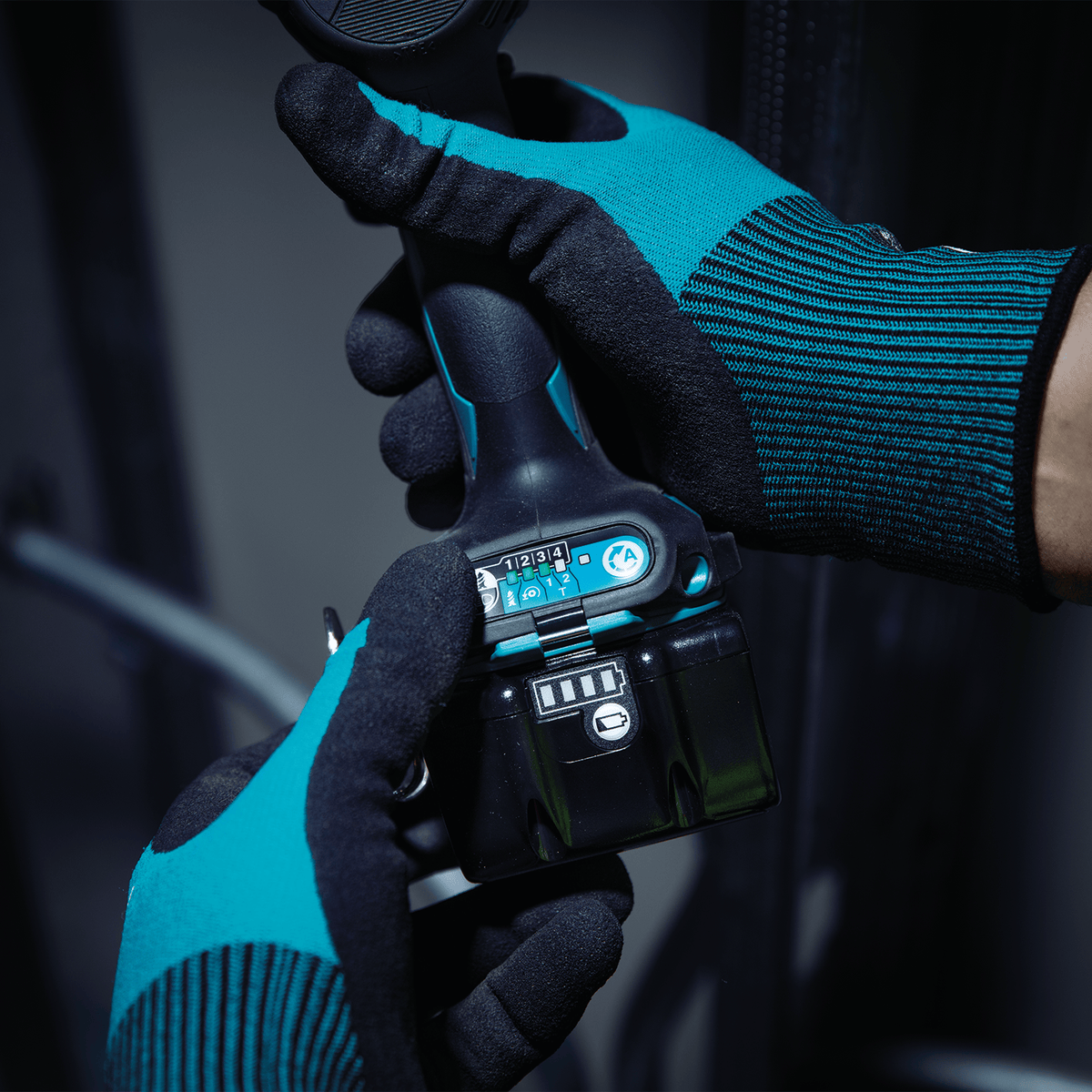 Technician wearing protective gloves selecting quick-shift electronic speed modes on the base panel of a Makita XDT20 impact driver.