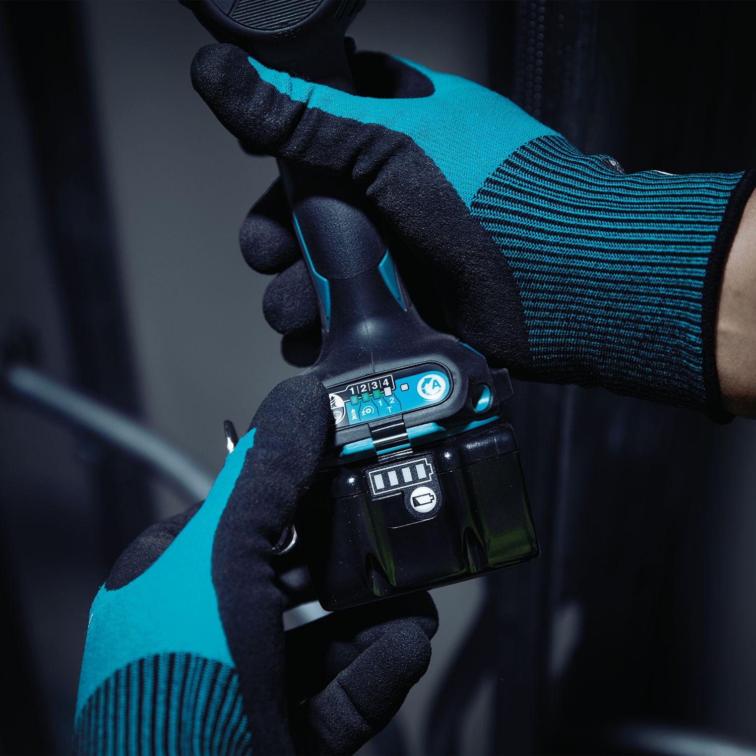 Technician wearing protective gloves selecting quick-shift electronic speed modes on the base panel of a Makita XDT20 impact driver.