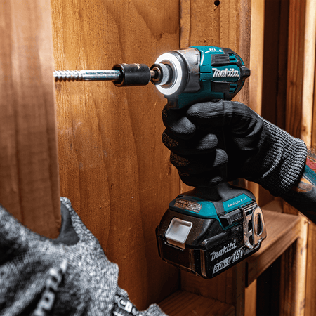 Contractor driving a structural lag bolt into a wood stud using a Makita XDT20 impact driver equipped with a 360-degree LED light ring.