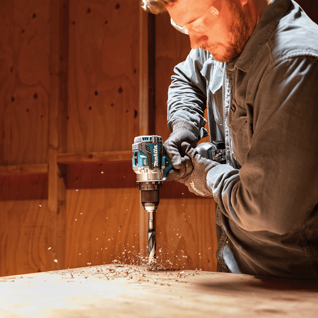 Tradesman using the Makita XFD16Z 18V brushless driver-drill with a spade bit to bore clean holes through wood subflooring.