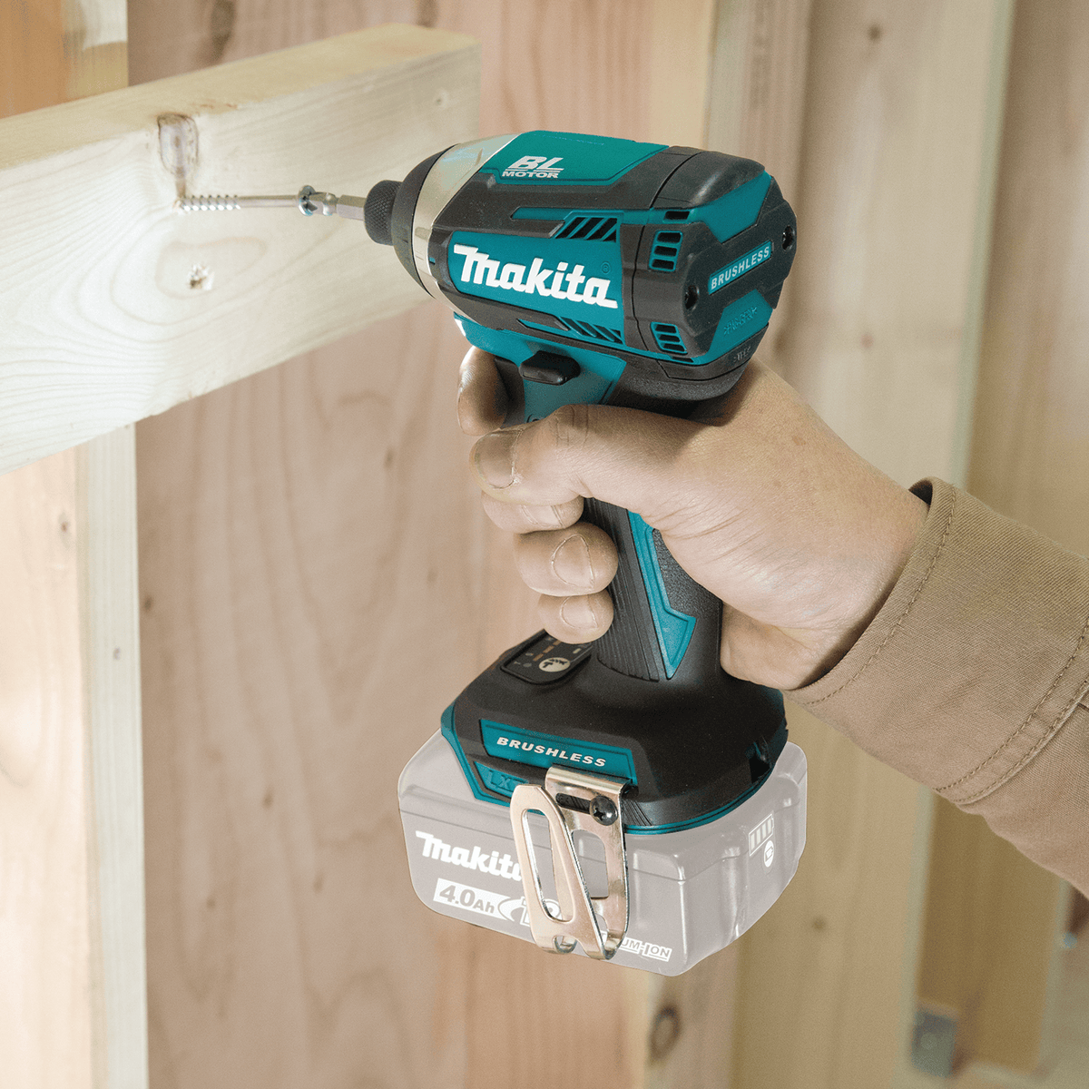 Fastening wood framing screws with the compact Makita XDT14Z 18V cordless brushless impact driver on a construction site.