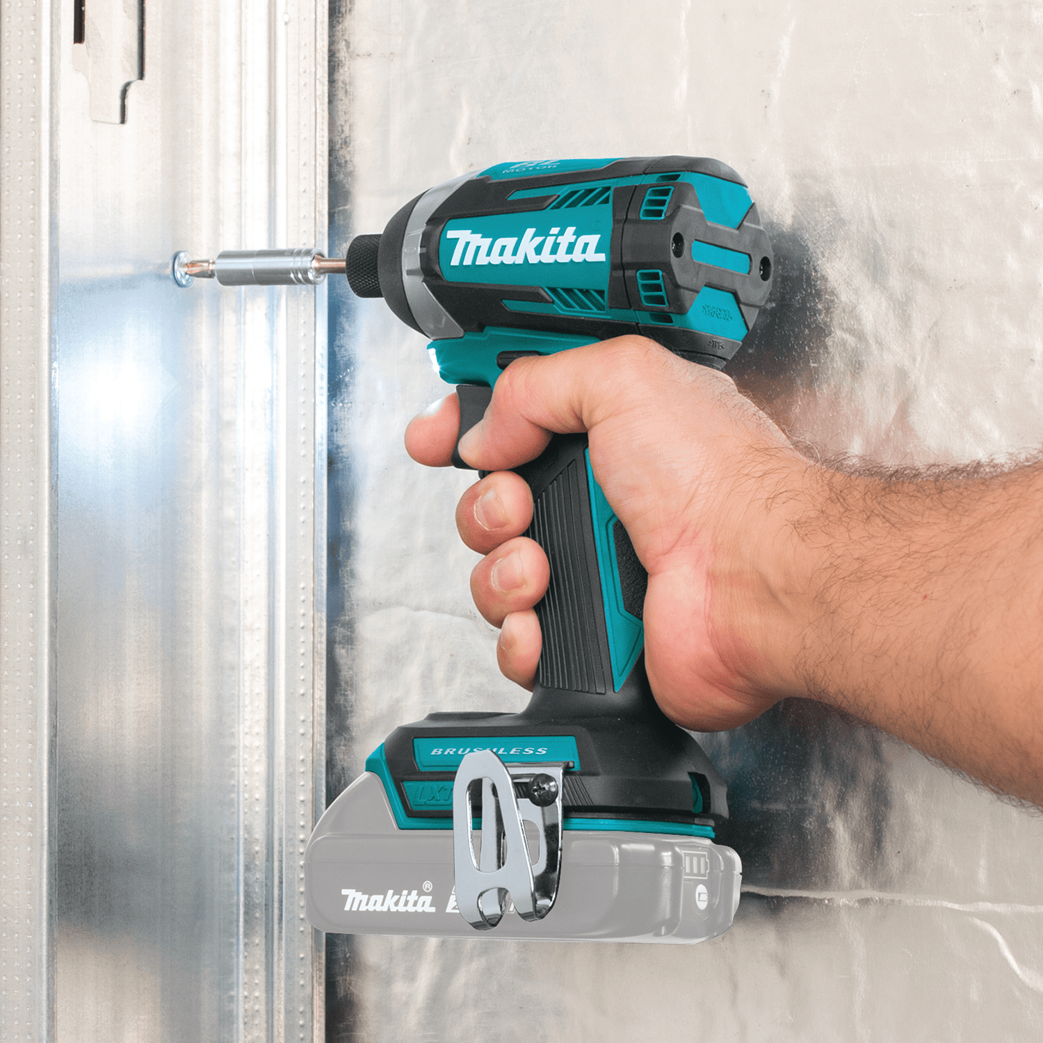 Worker uses the Makita XDT14Z 1/4-inch hex impact driver to drive self-tapping fasteners into commercial steel framing.